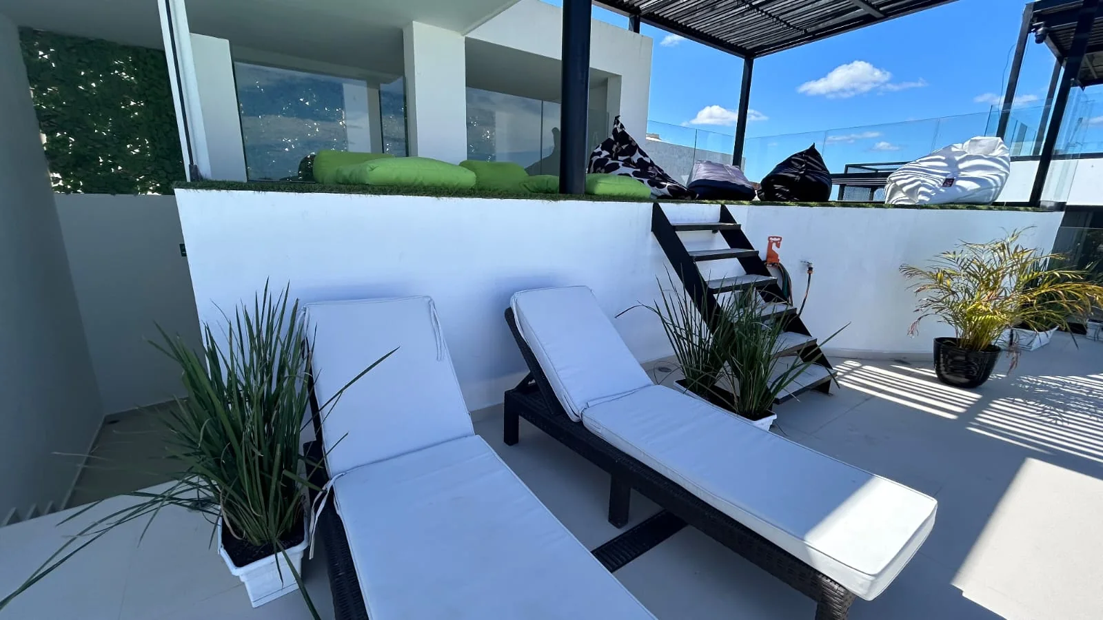 Terraza con camastros y plantas, lista para recibir huéspedes en Tulum